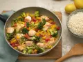 Leckeres Fischpfanne Rezept mit Lachs, Brokkoli und Paprika. Dazu eine Schüssel Reis.