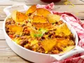 Herzhafter nacho auflauf mit Hackfleisch, Bohnen, Mais und geschmolzenem Käse, garniert mit Tortilla-Chips und frischen Kräutern.