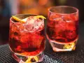Zwei klassische Negroni-Cocktails mit Eis und Orangenzeste. Das perfekte Rezept für einen originalen Negroni.