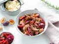 Herzhafte Rezepte mit Pflaumen: Ein Eintopf mit Fleisch, Pilzen und roten Zwiebeln, garniert mit frischen Pflaumen. Daneben eine Schüssel mit Nudeln.
