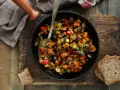 Ratatouille rezept: Buntes Gemüse aus Aubergine, Paprika und Karotten in einer Pfanne, serviert mit Brot.