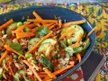 Herzhafte Salate mit Karottenstreifen, Gurkenscheiben, Edamame und zerrupftem Lachs. Knusprige Röstzwiebeln sorgen für Textur.