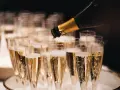 Sekt wird in Gläser gefüllt, die auf einem Tablett stehen. Die Bläschen steigen auf und erinnern daran, woher Champagner kommt.
