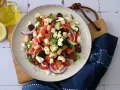 Frischer griechischer Bohnensalat mit Tomaten, Gurken, roten Zwiebeln, Oliven und Feta. Ein Spritzer Olivenöl und Zitrone machen ihn perfekt.