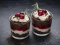 Zwei Gläser mit einem schnellen Dessert mit Kirschen: Schokoladenkuchen, Creme und Kirschen, garniert mit frischen Kirschen und Rosmarin.