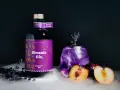 Ein magischer lila Gin Tonic mit Pflaume und Lavendel, daneben eine Flasche Sîmsala Gin.