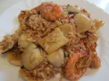 Ein köstlicher arroz de marisco mit Garnelen, Muscheln und Tintenfischstücken, serviert auf einem weißen Teller.