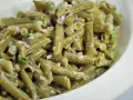 Grüner Bohnensalat mit cremigem Dressing, roten Zwiebeln und Kräutern in einer weißen Schüssel.