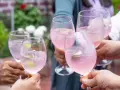 Hände stoßen mit rosafarbenen Sarto Spritz-Cocktails mit Limette und Eis an.