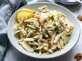 Frischer sellerie salat mit Äpfeln, Walnüssen und Kräutern, garniert mit einer Zitronenspalte.