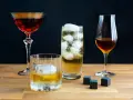 Vier Gläser mit verschiedenen Getränken, darunter ein Whisky-Cocktail, ein Highball und ein Nosing-Glas. So trinkt man Whisky: pur, mit Eis oder als Mixgetränk.