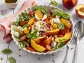 Erfrischender Salat mit saftigen Nektarinen, Tomaten, Mozzarella und Rucola, beträufelt mit Balsamico-Dressing.