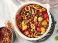 Ein bunter Nudelsalat mal anders: Orecchiette mit Kichererbsen, Kirschtomaten, Oliven und Kräutern in einer Auflaufform. Daneben eine Schale mit Gewürzmischung.