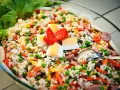 Reissalat mit Erbsen, Karotten, Ei und Wurst – ein gesunder Salat zum Grillen, garniert mit Tomaten und Salatblättern.