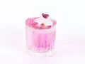 Ein erfrischender Gin Mix in zartem Rosa, garniert mit Rosenblättern und einer kleinen Knospe auf einem Eiswürfel.