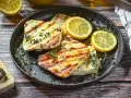 Perfekt gegrillter Halloumi mit Kräutern und Zitronenspalten auf einer Gusseisenplatte. Ein Genuss für alle Sinne!