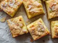 Saftiger Buttermilch Kuchen mit Mandelblättchen und Puderzucker bestreut, auf Backpapier arrangiert.