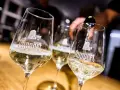 Drei Gläser mit schäumendem Wein, der von einer Flasche in das vorderste Glas gegossen wird. Der Wein aus mehreren Rebsorten ist von der Marke Ruppert.