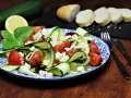 Ein erfrischender, sommerlicher Zucchini-Salat mit Tomaten und Feta, garniert mit Basilikum und Balsamico. Dazu Baguettescheiben.