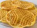 Goldbraune Herz-Waffeln, frisch gebacken aus waffelteig ohne butter, liegen auf einem Gitter.