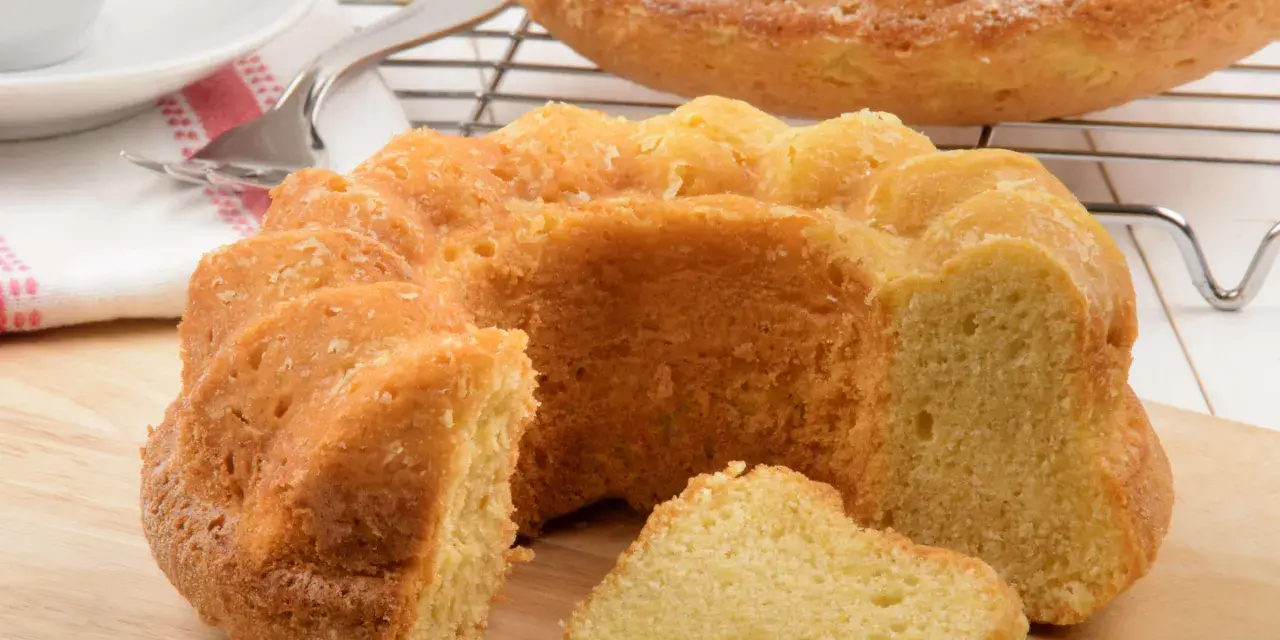 Ein goldbrauner Paradiescreme Kuchen, frisch gebacken und mit einem Stück abgetrennt, wartet auf Genuss.