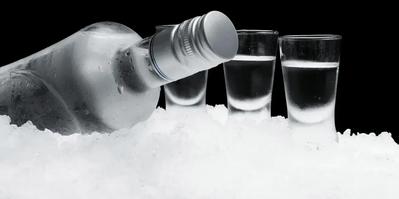 Eiskalte Flasche Wodka und drei Shotgläser auf Eis. So schmeckt Wodka am besten: rein und erfrischend.