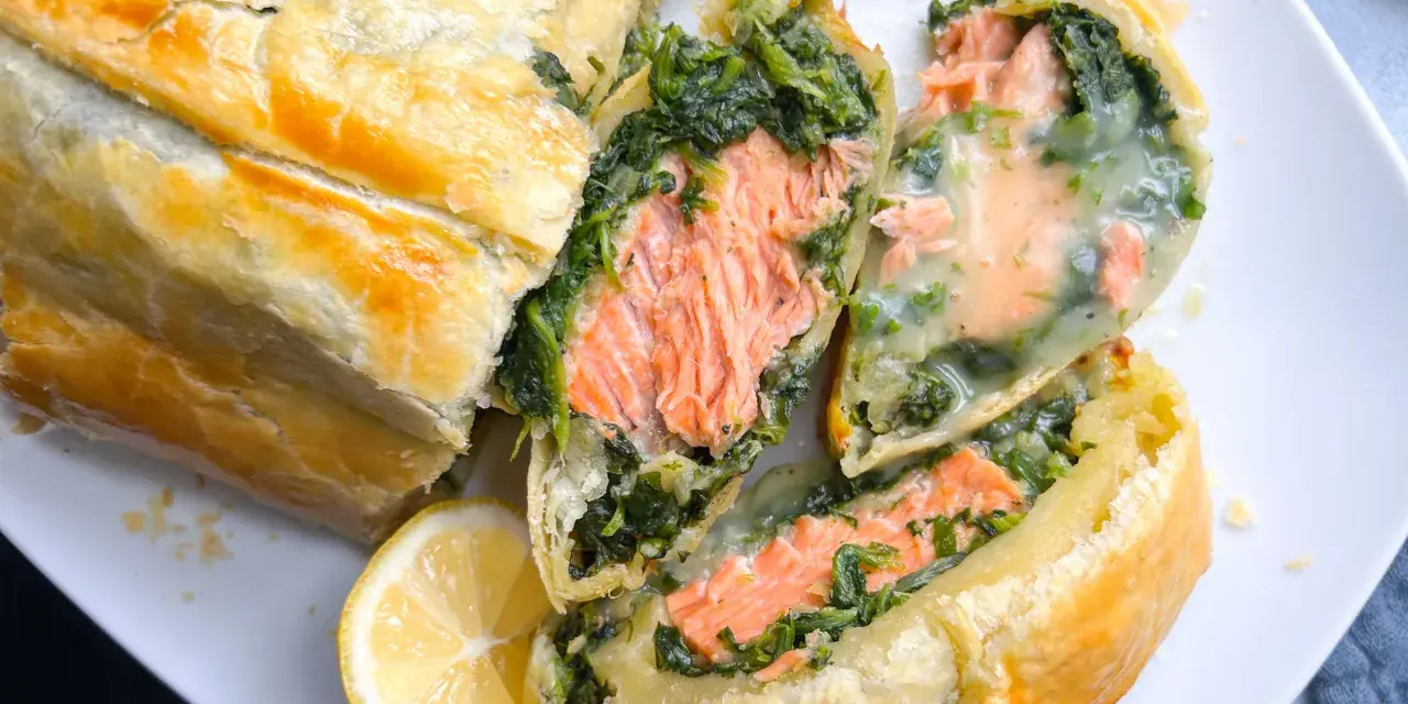 Saftiger Lachs mit Spinat in Blätterteig, ein köstliches Gericht für Fisch-Rezepte. Dazu eine Zitronenspalte.