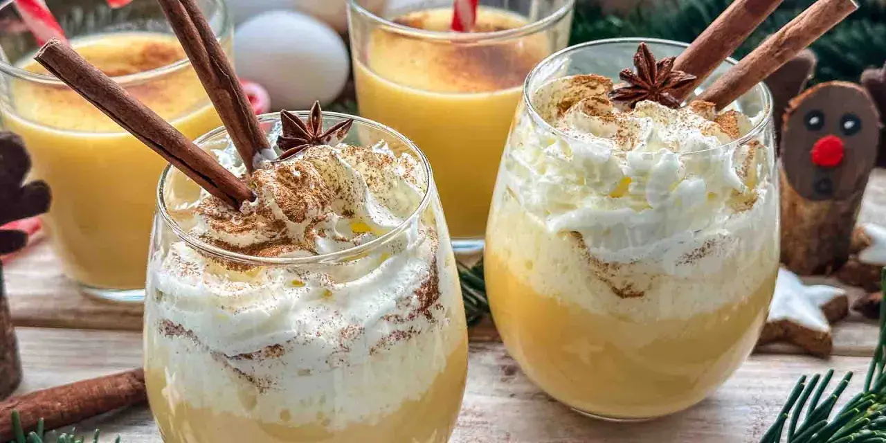 Festliche Gläser mit cremigem Eggnog, garniert mit Zimtstangen und Schlagsahne. Das perfekte Eggnog Rezept original für Weihnachten.