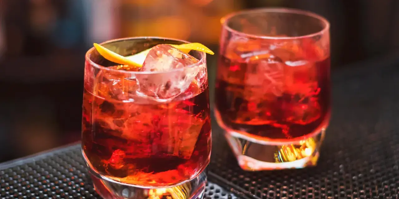 Zwei klassische Negroni-Cocktails mit Eis und Orangenzeste. Das perfekte Rezept für einen originalen Negroni.