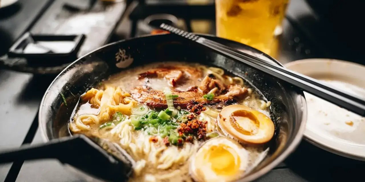 Eine dampfende Schüssel Ramen mit Nudeln, Fleisch, Ei und Frühlingszwiebeln. Das ist, was Ramen ist: ein herzhaftes japanisches Gericht.