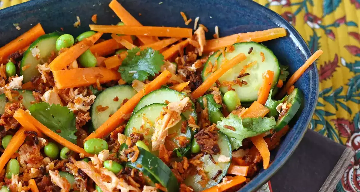 Herzhafte Salate mit Karottenstreifen, Gurkenscheiben, Edamame und zerrupftem Lachs. Knusprige Röstzwiebeln sorgen für Textur.