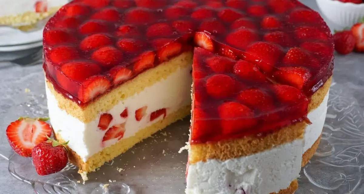 Eine **einfache Torte** mit Biskuit, Sahne und vielen frischen Erdbeeren unter rotem Tortenguss. Ein Stück ist bereits angeschnitten.