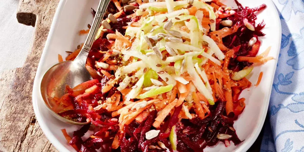 Bunter Salat aus geriebener roter Bete, Karotten und Apfelstiften, garniert mit Sonnenblumenkernen.