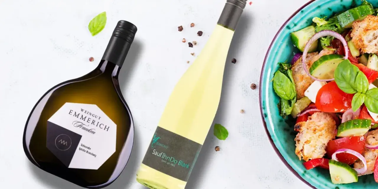 Zwei Flaschen Wein, eine davon eine Scheurebe mit fruchtigem Geschmack, neben einem frischen Salat.
