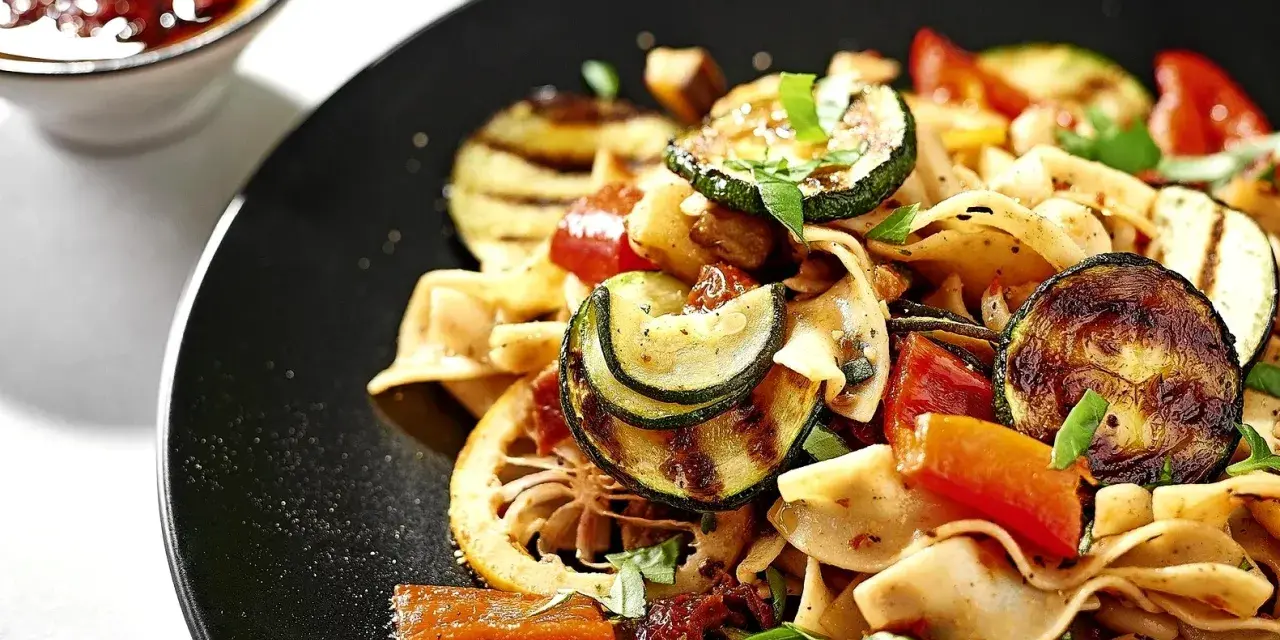 Ein bunter Nudelsalat mit gegrilltem Gemüse, Tomaten und Kräutern. Dazu passen Oliven perfekt.