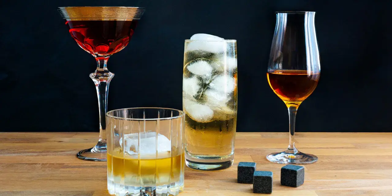 Vier Gläser mit verschiedenen Getränken, darunter ein Whisky-Cocktail, ein Highball und ein Nosing-Glas. So trinkt man Whisky: pur, mit Eis oder als Mixgetränk.