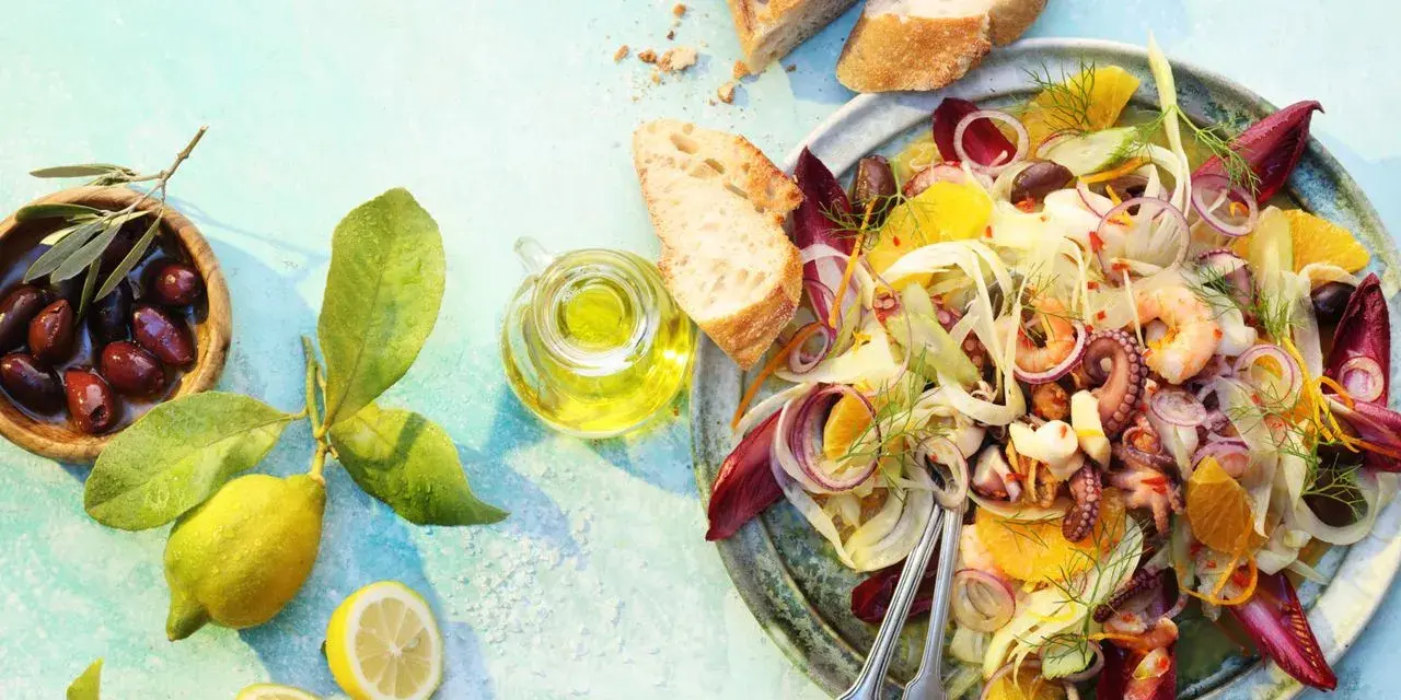 Raffinierte Sommersalate: Ein bunter Meeresfrüchtesalat mit Fenchel, Orange und Oliven, serviert mit Brot und Zitrone.