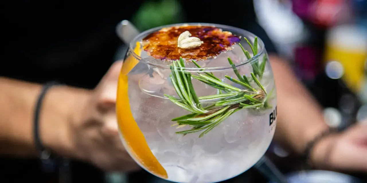 Ein erfrischender Gin Tonic mit Rosmarin und karamellisierter Orangenscheibe. Perfekt für einfache Gin Rezepte.