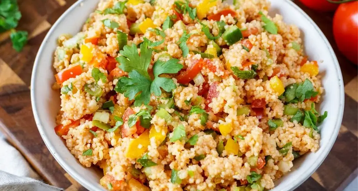 Bunter Couscous-Salat mit Tomaten, Paprika und Petersilie, garniert mit einem Petersilienblatt.