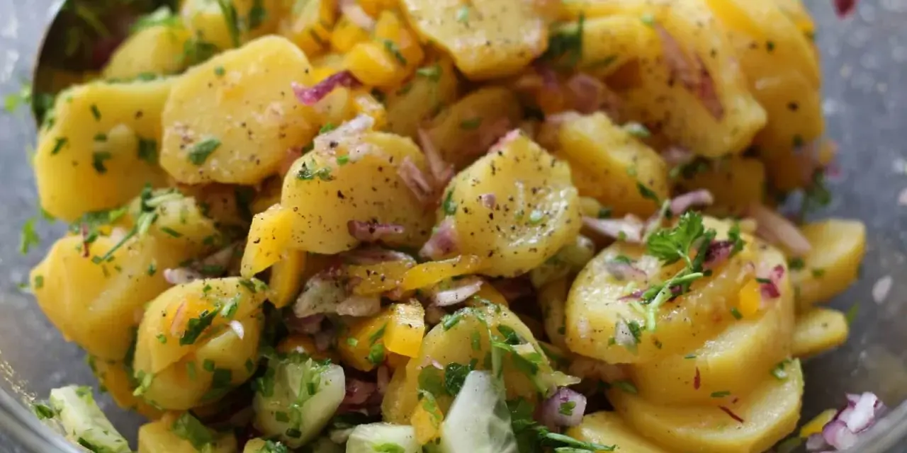 Omas sonntagsessen: Kartoffelsalat mit Gurken, Zwiebeln und frischen Kräutern, perfekt gewürzt.