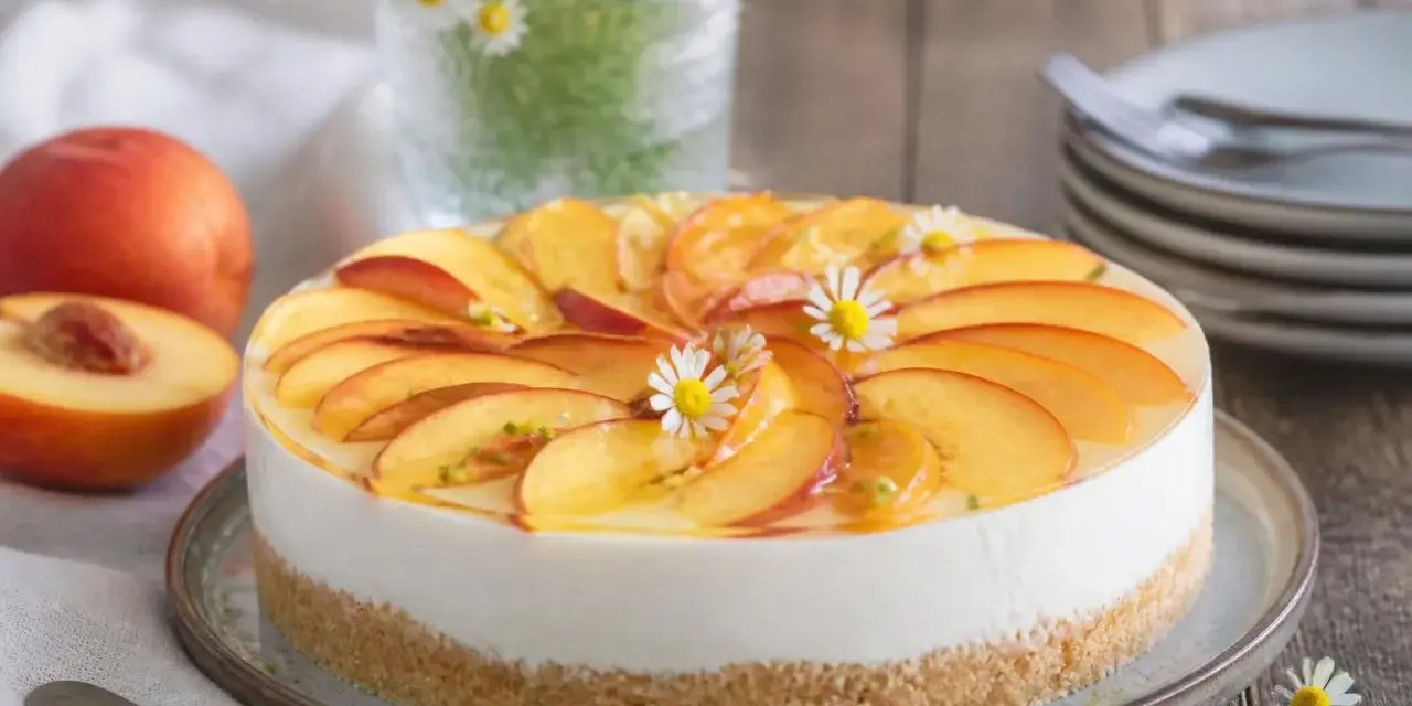 Eine **schnelle Torte** mit Pfirsichscheiben und Götterblümchen auf cremigem Käsekuchenboden.