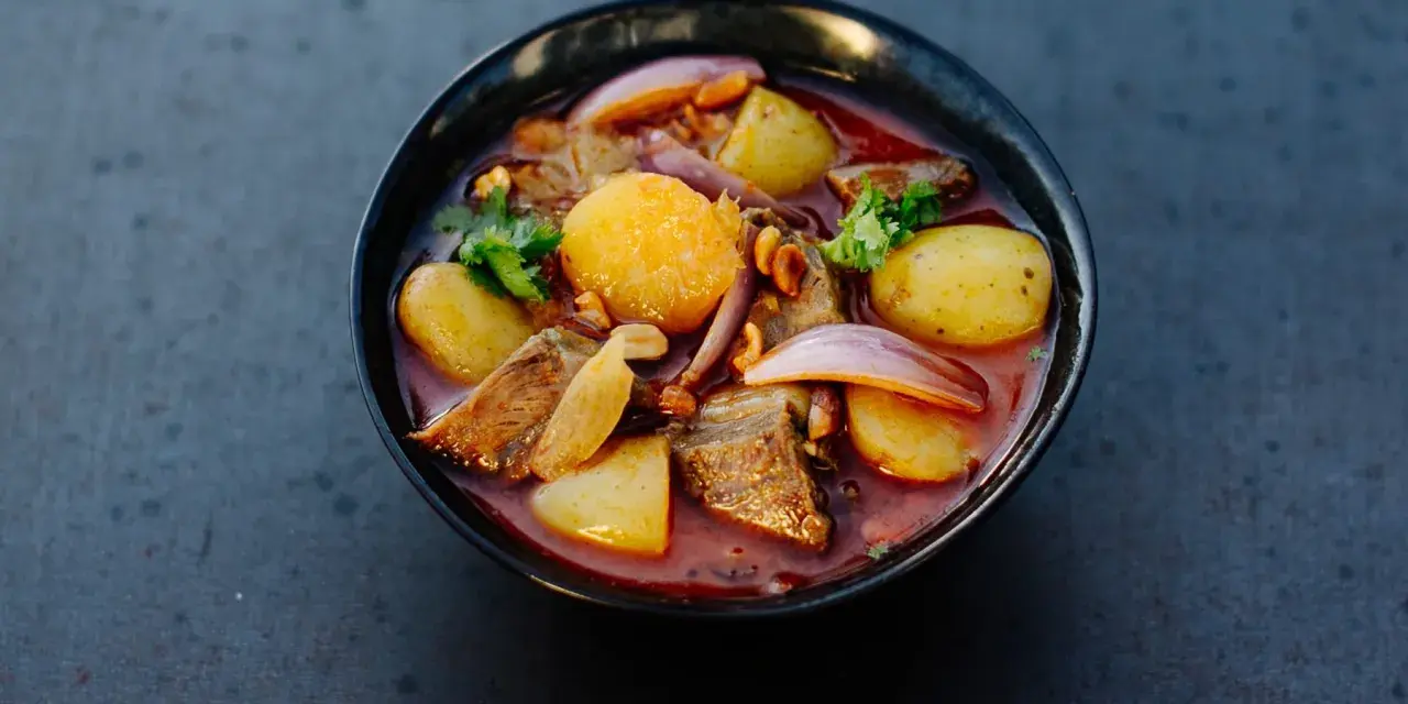 Schüssel mit Massaman Curry, Kartoffeln, Fleisch, Zwiebeln und Koriander.