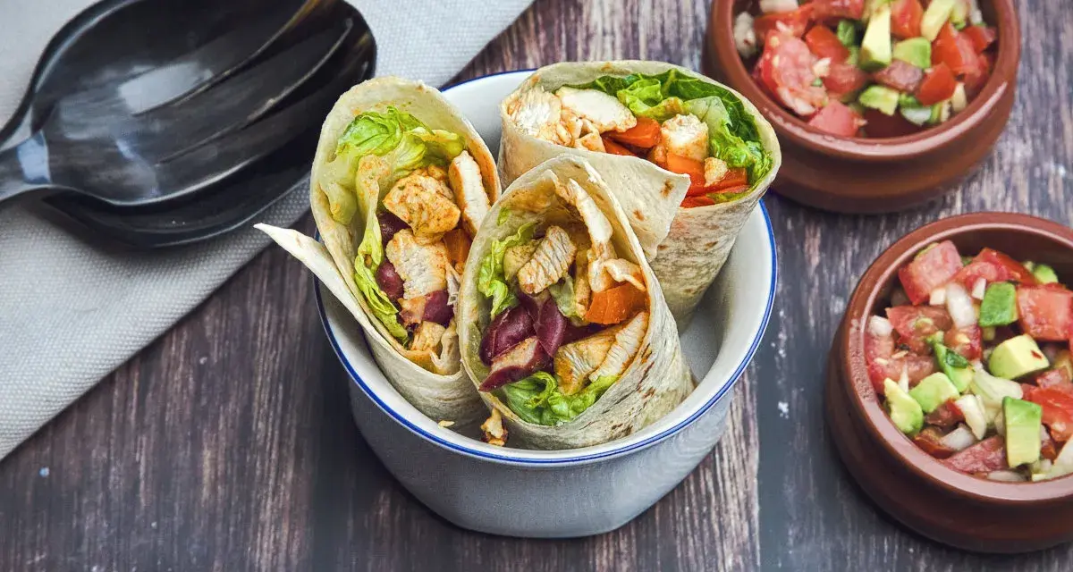 Drei leckere Wraps mit Hähnchen, Salat und Bohnen, perfekt zum Mexicana selber machen. Dazu frische Salsa in kleinen Schalen.