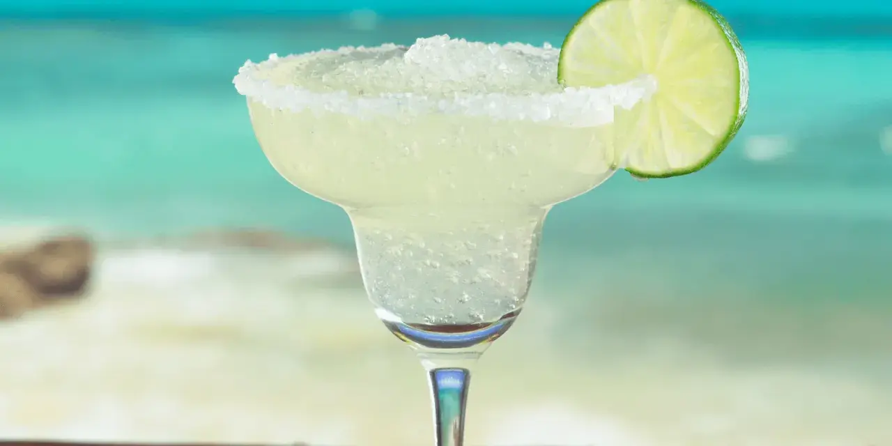Erfrischende Margarita mit Salzrand und Limettenscheibe, perfekt für ein Strand-Margarita-Rezept.