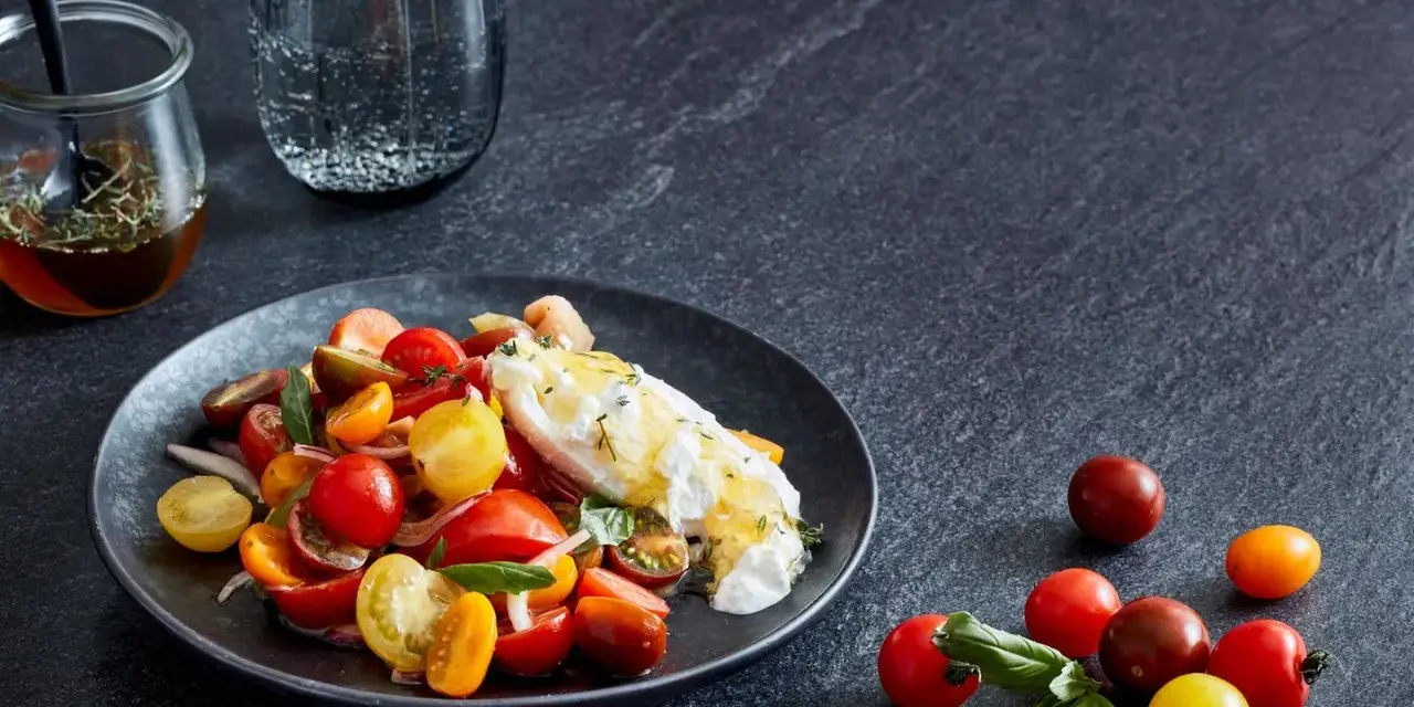 Bunter Tomatensalat mit cremiger Burrata, garniert mit frischen Kräutern. Ein köstlicher Genuss!
