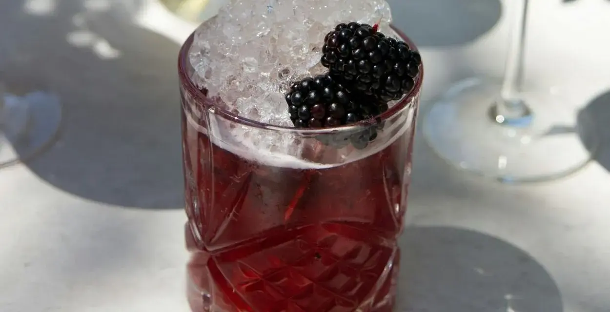Erfrischender Brombeer-Cocktail mit zerstoßenem Eis und frischen Beeren. Perfekt für sommerliche longdrink rezepte.