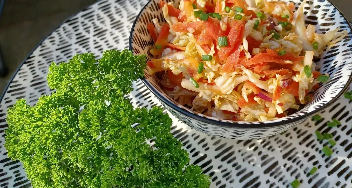 Frischer Chinakohlsalat mit Honig-Senf Dressing, garniert mit Lachs und Schnittlauch. Daneben ein Bund glatte Petersilie.