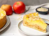 Ein saftiges Stück Apfel Schmand Torte mit Mandelsplittern, daneben Äpfel und eine Schale mit Streuseln.