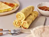 Gestapelte Quark Pfannkuchen, goldbraun gebacken, mit einer Schale Marmelade und Gabeln daneben.