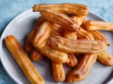Goldbraune Churros, frisch aus dem Airfryer, mit Zucker bestreut auf einem grauen Teller.